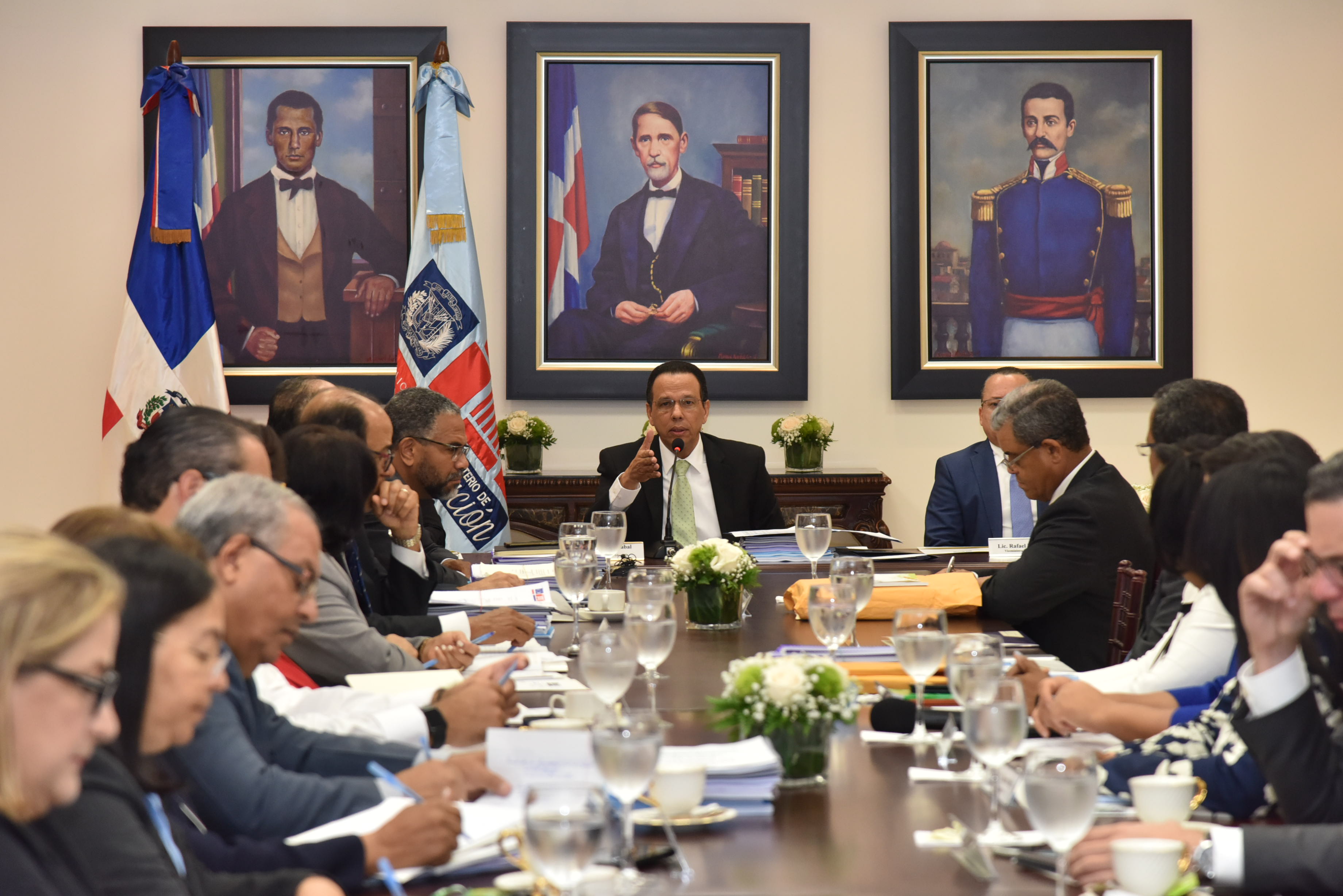  imagen Sentados a la mesa, en el centro Ministro Peña Mirabal junto a demás personalidades durante sesión. 