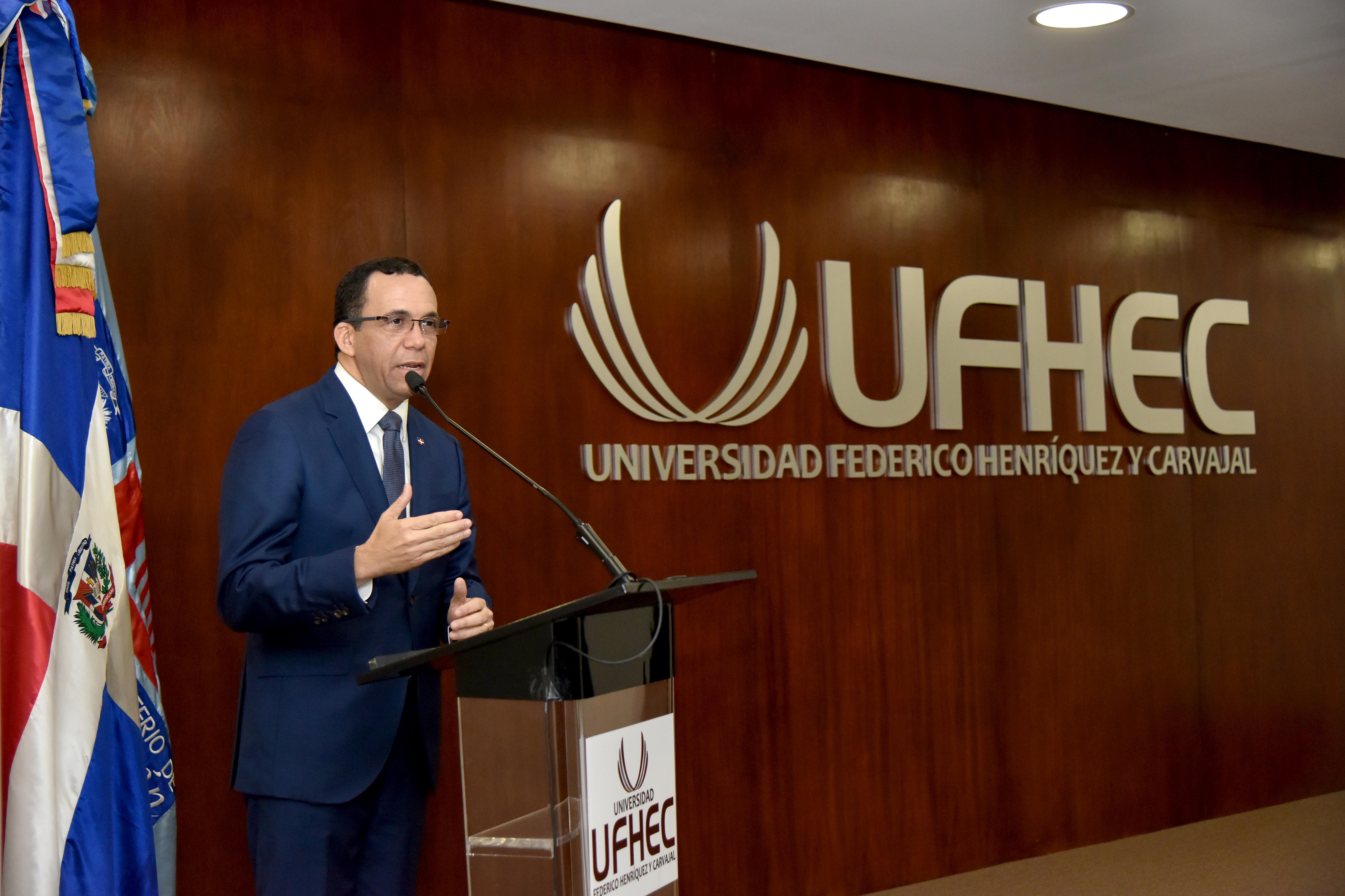  imagen Ministro Andrés Navarro de pie en podium dirigiendo discurso a personas en auditorium de la universidad Federico Henríquez y Carvajal  