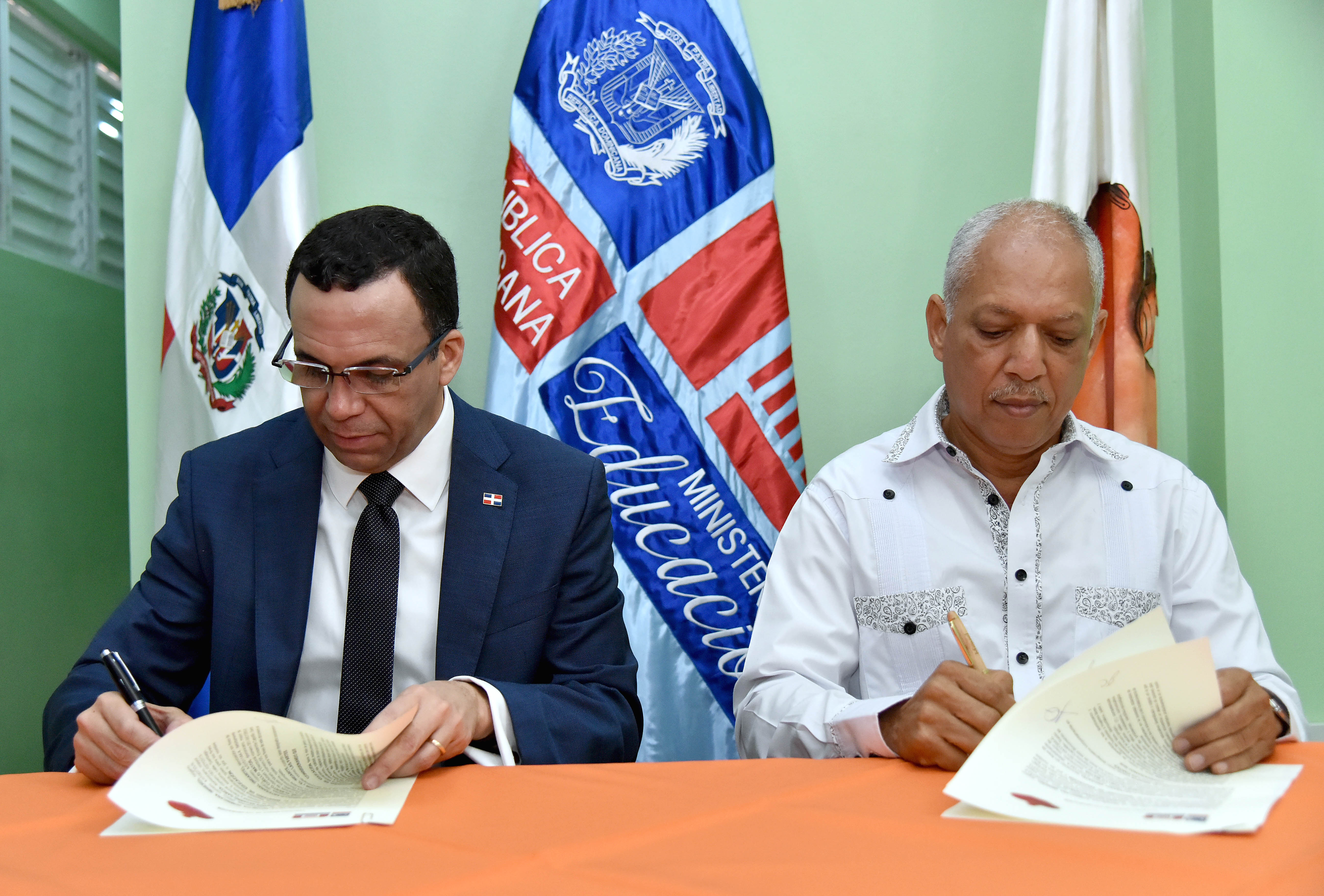  imagen Ministro Andrés Navarro y director de INDARTE  sentados firmando acuerdo de cooperación para promover el arte en las escuelas de Capotillo  