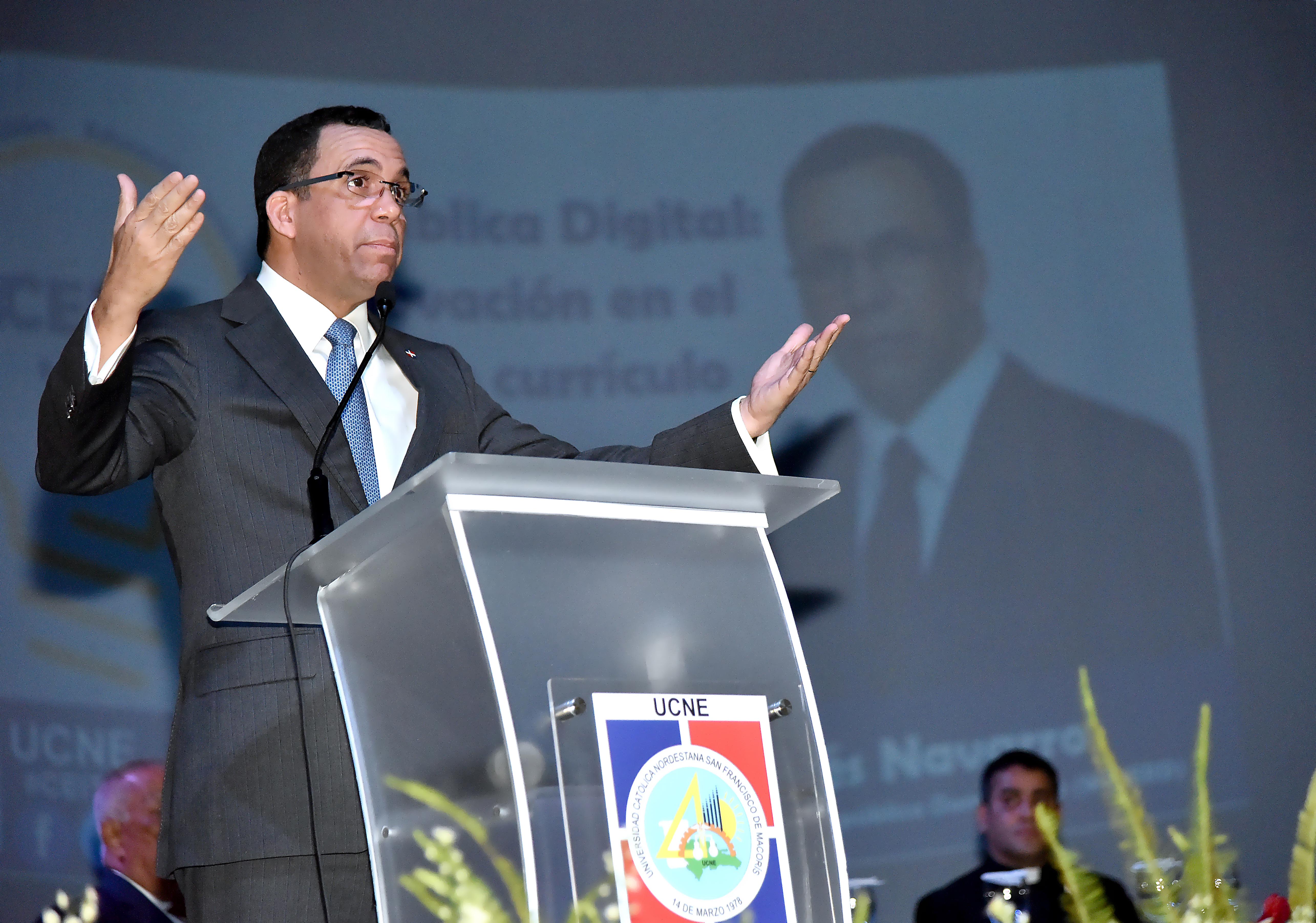  imagen Ministro Andrés Navarro de pie en podium exponiendo discurso al lado de mesa principal en posgrado de la Universidad Católica Nordestana 