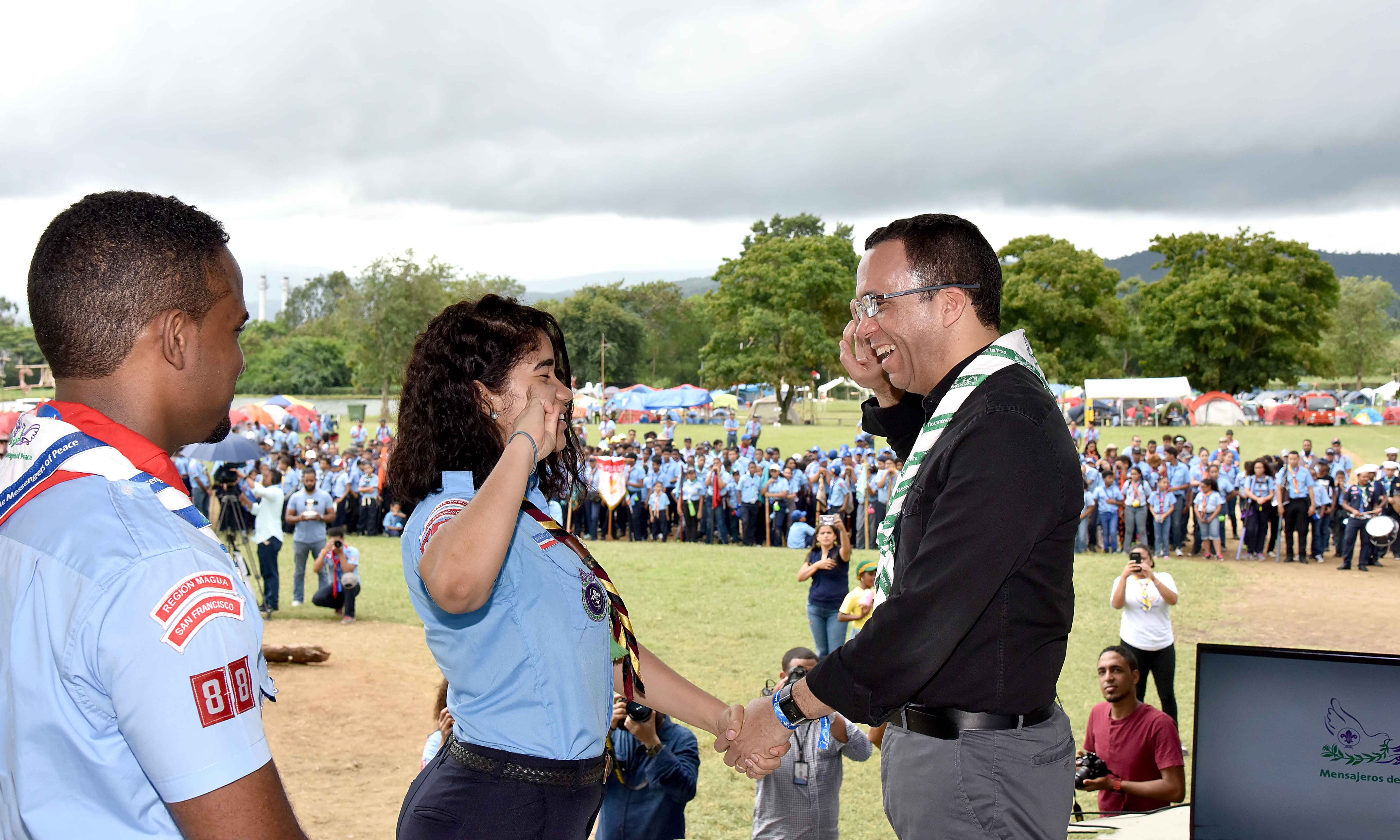  imagen Ministro Andrés Navarro de pie estrechando saludos a joven líder del movimiento Scouts  