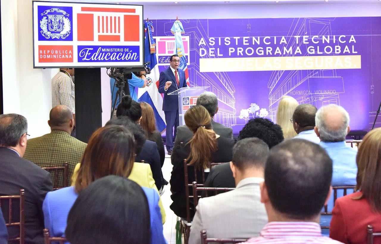  imagen Ministro Andrés Navarro parado desde podium expone programa Escuelas Seguras frente a directivos del banco mundial y viceministros y autoridades del Ministerio  