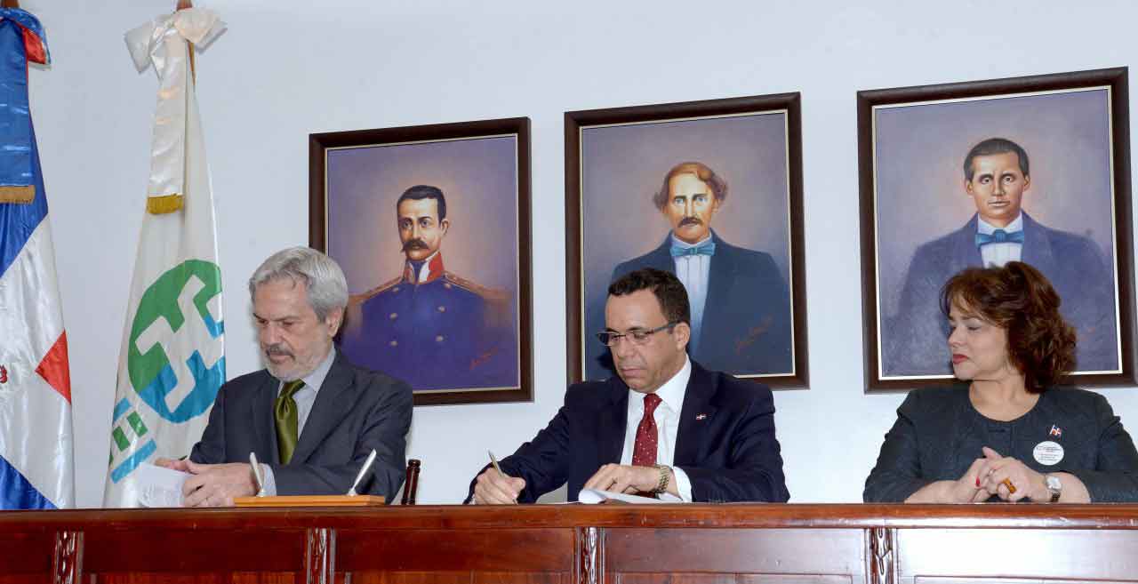  imagen En el centro de la mesa directiva Ministro Andrés Navarro firma documentación, a su derecha el señor Paulo Speller y a su izquierda la señora Yokasta Guzmán. 