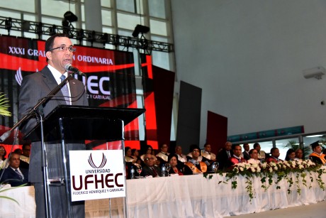  imagen Ministro Andrés Navarro de pie en podium dirigiendo discurso a cientos de profesionaes en XXXI Graduación Ordinaria de la Universidad Federico Henríquez y Carvajal (UFHEC). 